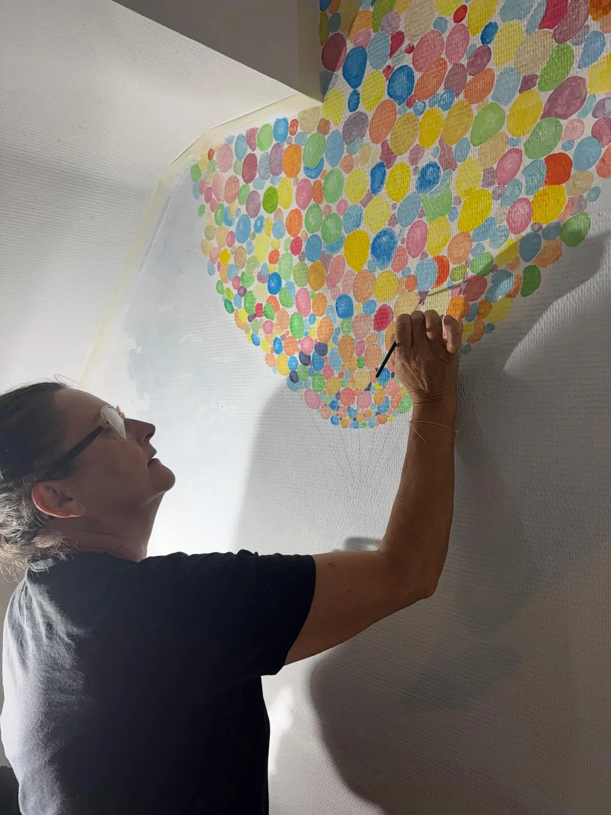Sylvie en train de peindre les ballons d'une fresque murale